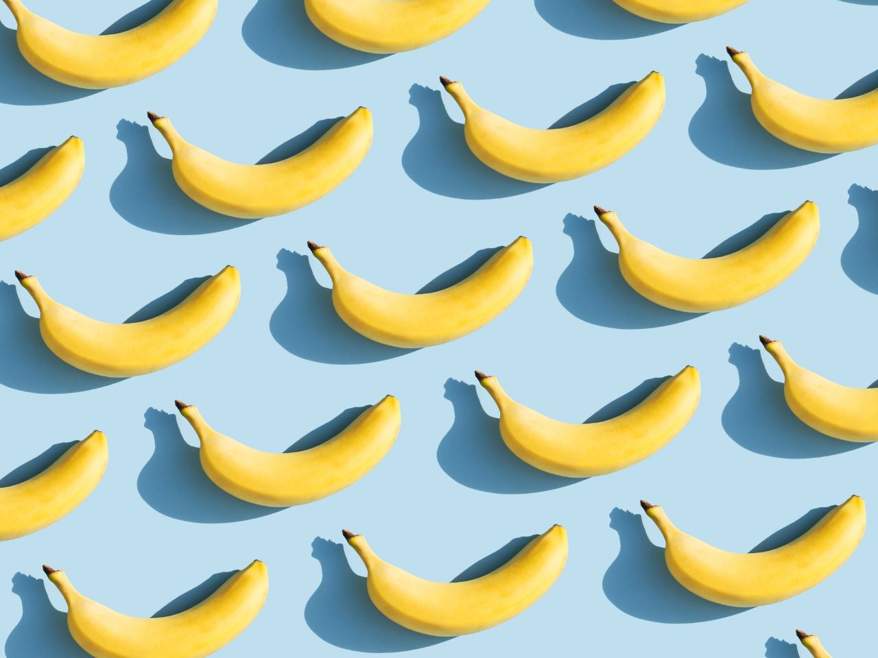 Symmetrisch angeordnete Bananen auf hellblauem Hintergrund aus der Vogelperspektive