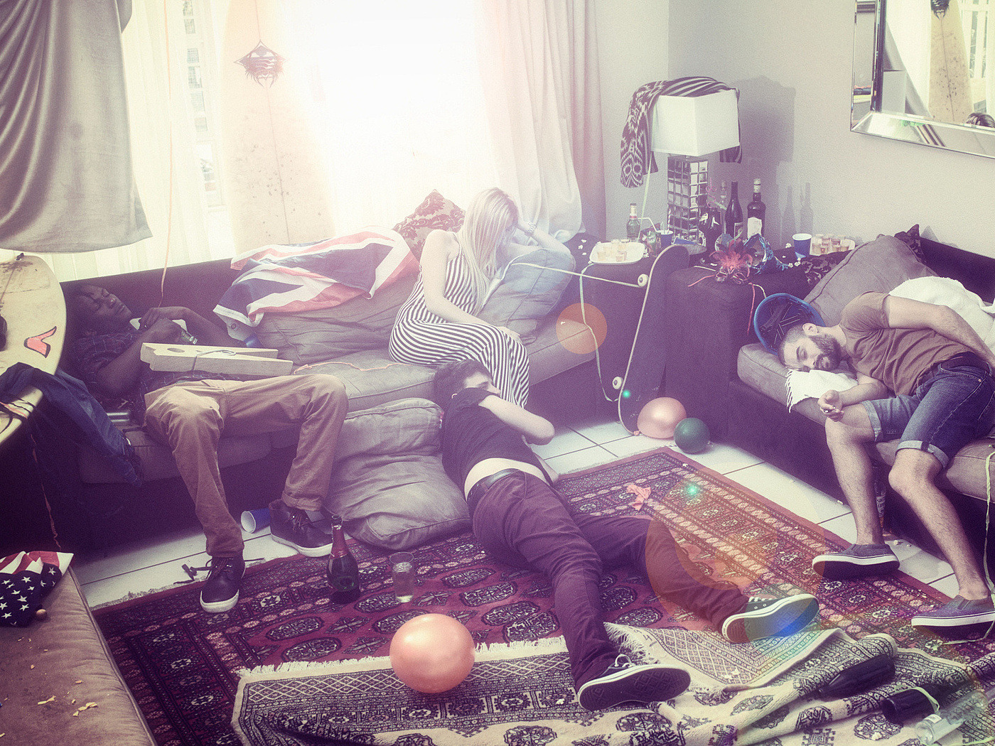 Jugendliche schlafen nach einer Party auf und neben Sofas.
