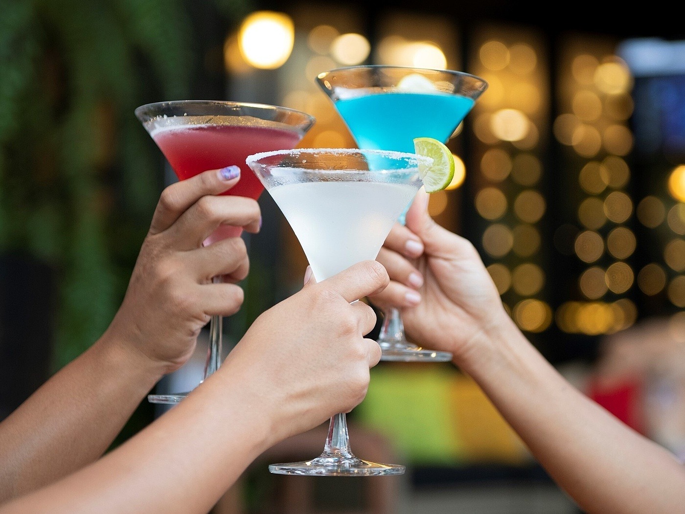 Drei Leute stoßen mit alkoholfreien Cocktails an