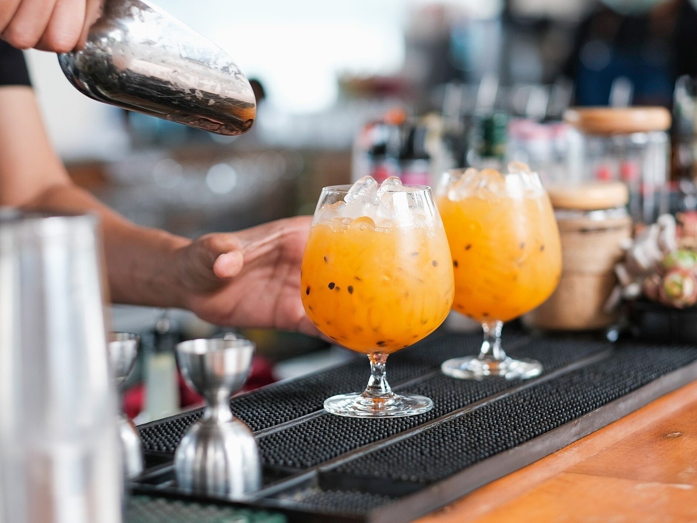 Barkeeper bereitet 2 orangefarbene Cocktails zu