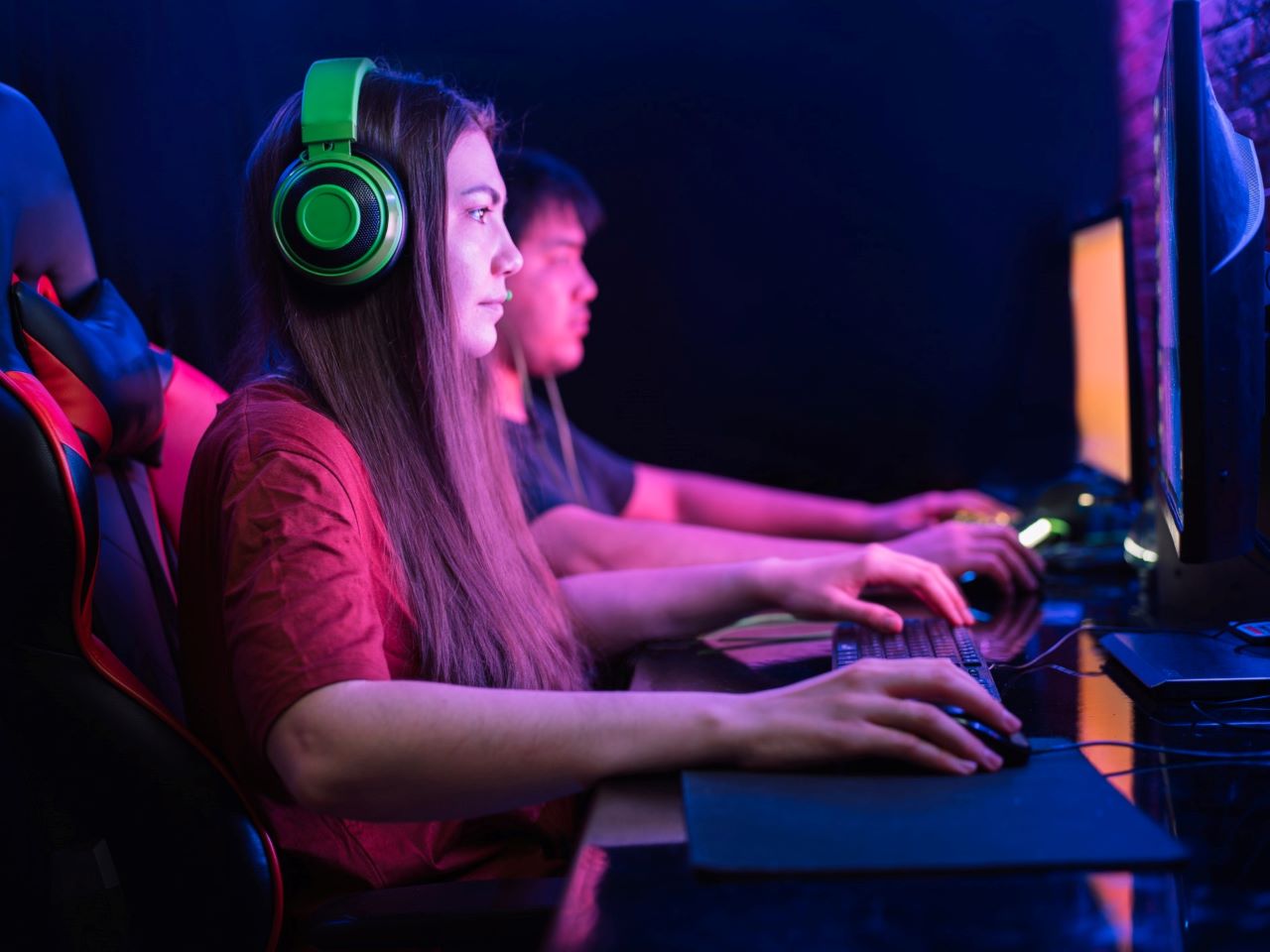 2 Jugendliche sitzen bei einem eSport-Turnier nebeneinander an PCs und spielen